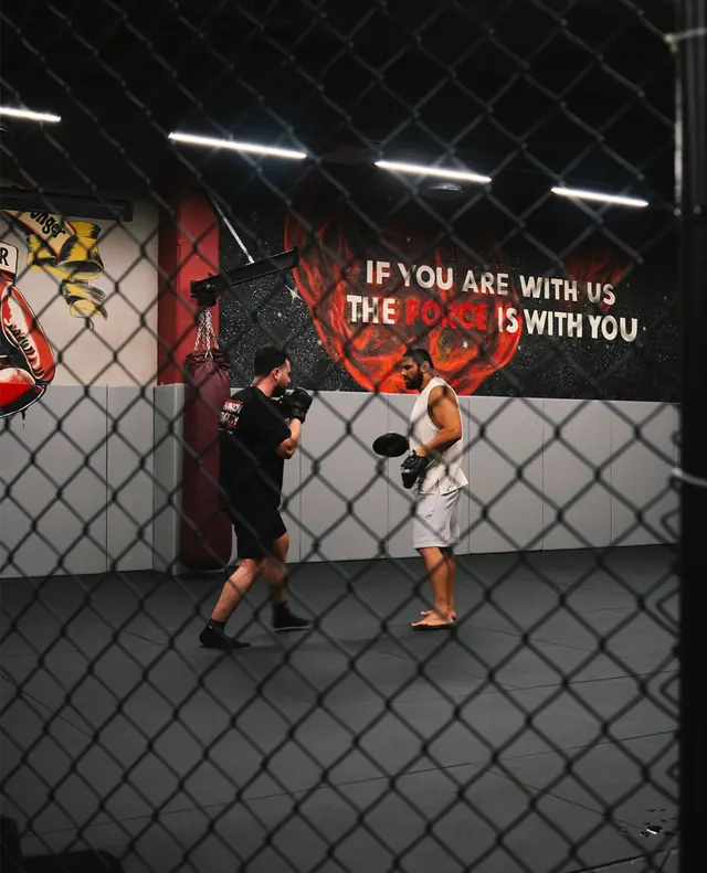 Kafes alanında pedle boks çalışan antrenör ve sporcu